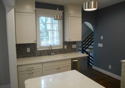 Renovated kitchen with white cabinets and modern stairwell. This house was renovated after a fire damage.