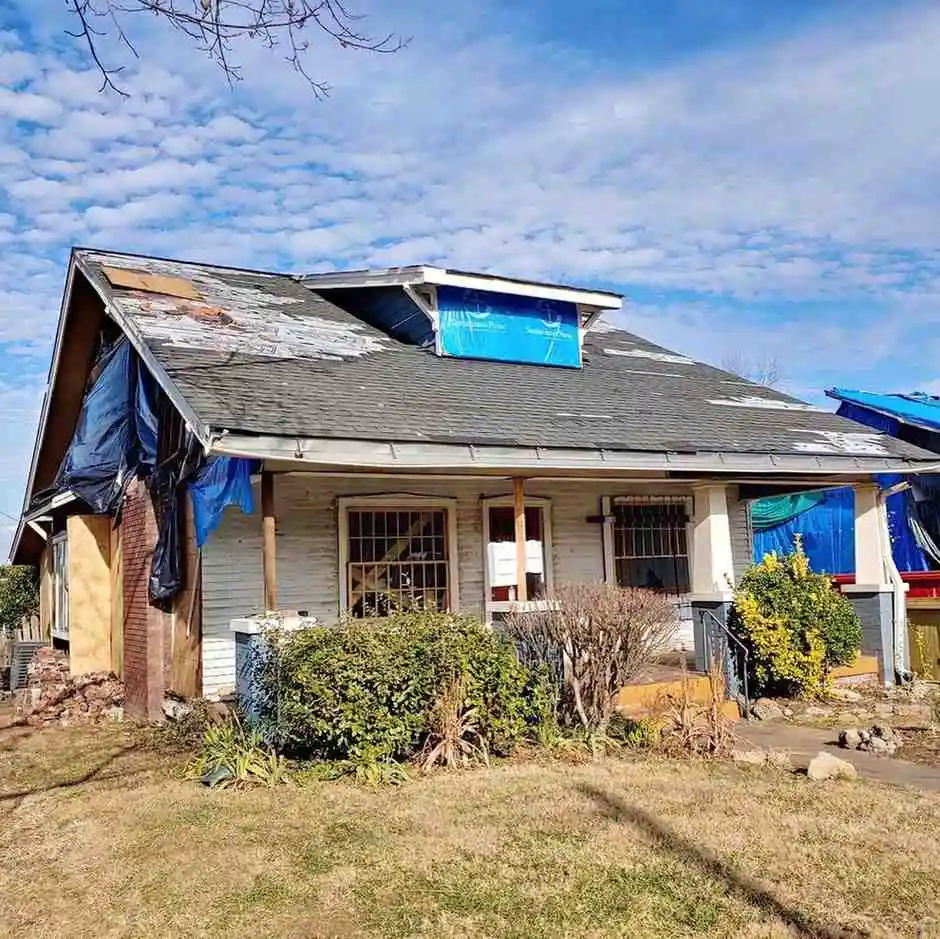 Storm damaged exterior of a home Residential home exterior showing heavy roof and siding storm damage