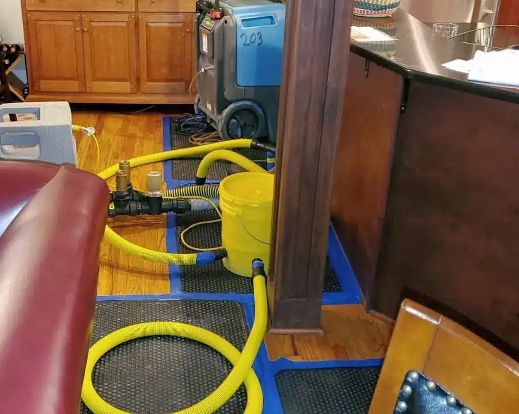 Drying mats and yellow hoses set up on hardwood floors during water damage restoration in Nashville